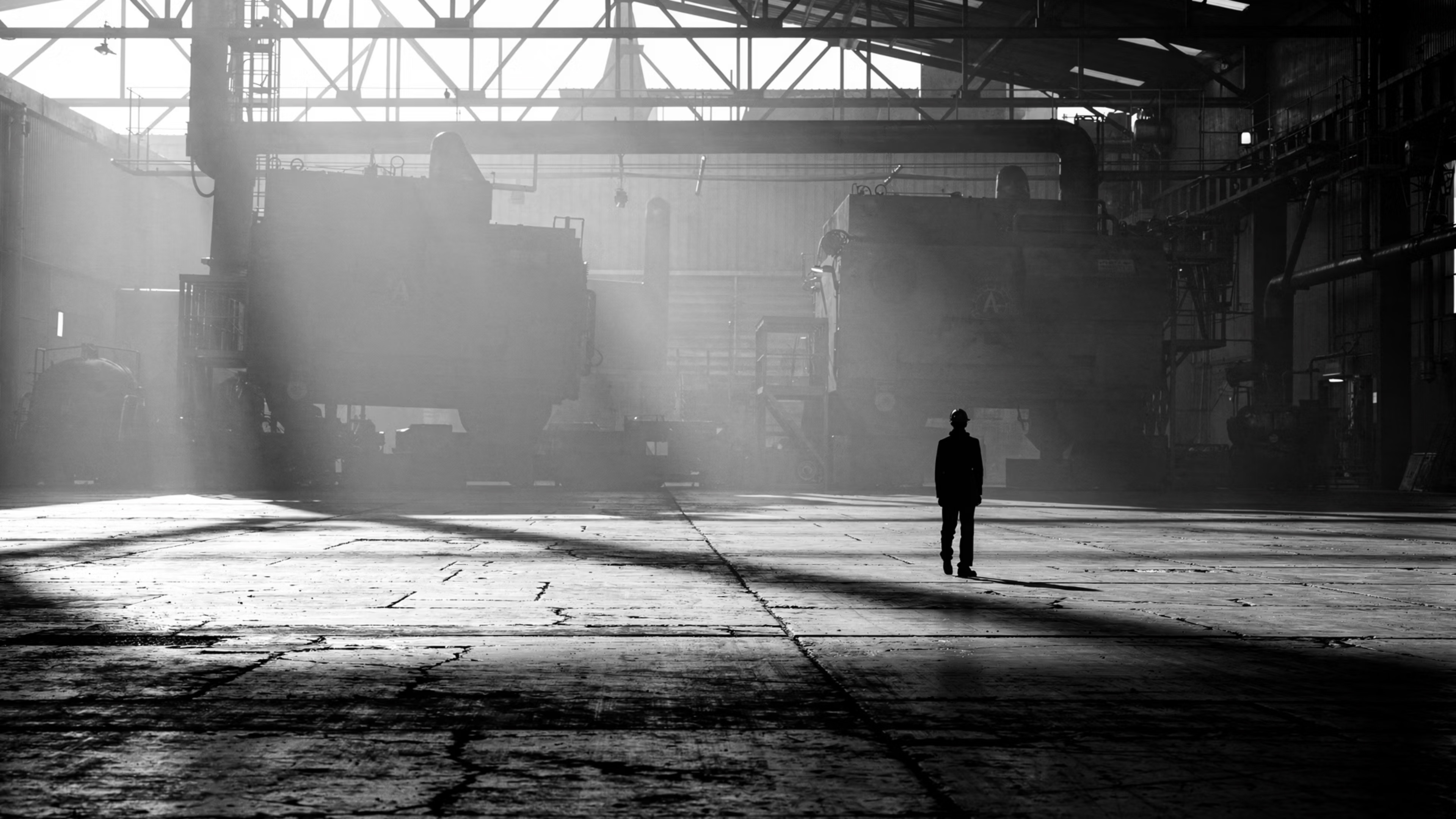 Manufacturing leader standing alone in a vast industrial facility under production pressure